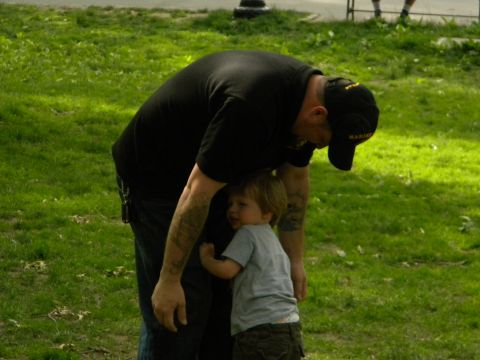 1992 Ford Bronco - A man embraces a young child in a park setting, with green grass and trees in the background.