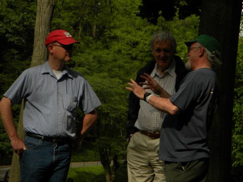 1992 Ford Bronco - Three men engage in conversation outdoors amidst trees, with one man wearing a red baseball cap.