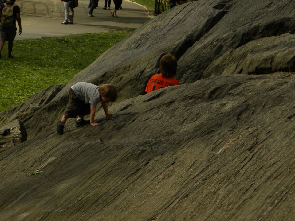 Children climbing on a rocky incline with people in the background