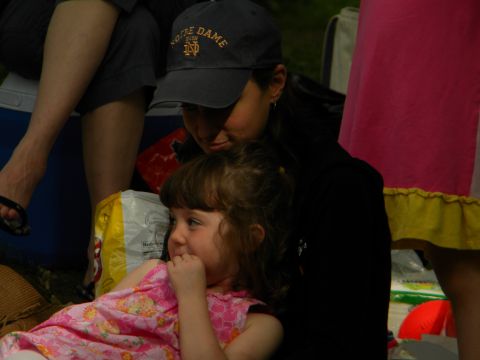 1992 Ford Bronco - A woman wearing a Notre Dame baseball cap looks down at a young girl in a pink dress, with other people visible in the background.