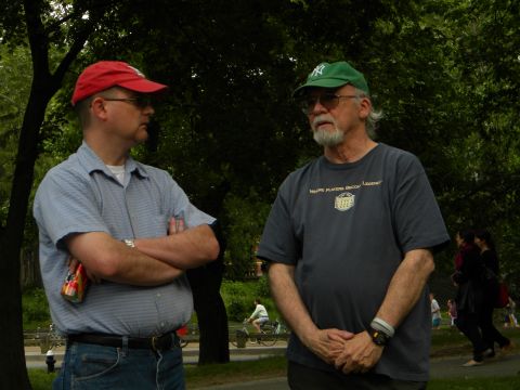 1992 Ford Bronco - Two men converse in a park setting, with trees and other people in the background.