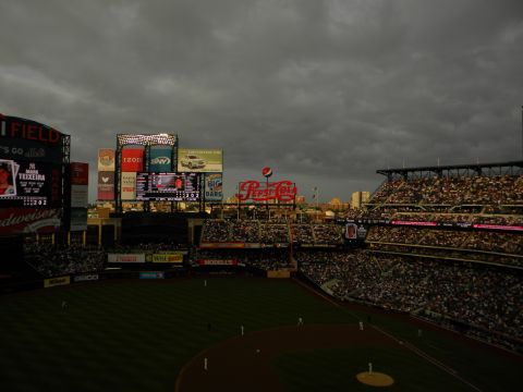 1992 Ford Bronco - A baseball stadium filled with spectators under a dramatic, cloudy sky, with multiple large scoreboards visible.