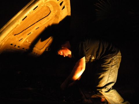 1992 Ford Bronco - A person works on a car's engine at night, with the hood open and illuminated.