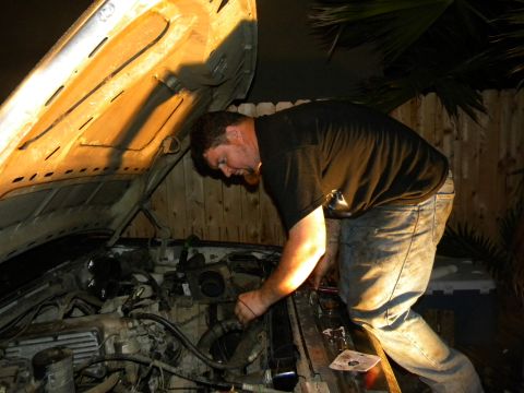 1992 Ford Bronco - A man works on the engine of a 1992 Ford Bronco under the hood.