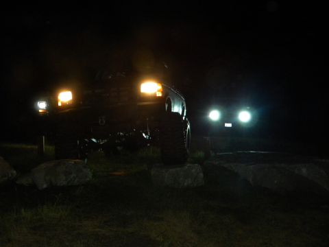 1992 Ford Bronco - Two SUVs are parked at night, with their headlights illuminated.