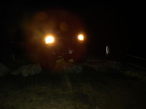 1992 Ford Bronco - A dark SUV is seen from the front at night, its headlights illuminating the scene.