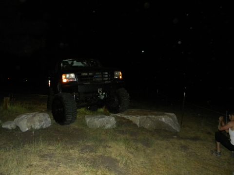 1992 Ford Bronco - A modified truck navigates an obstacle course at night, with a spectator observing the action.