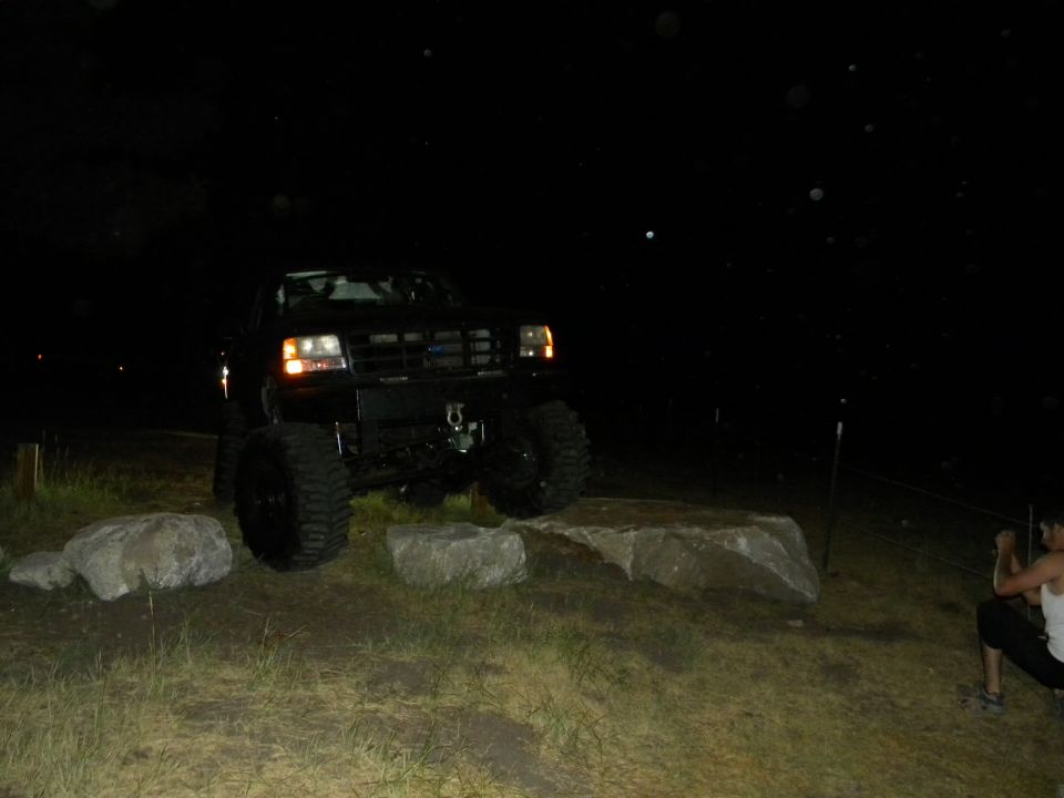 black lifted truck on rocks at night, person watching