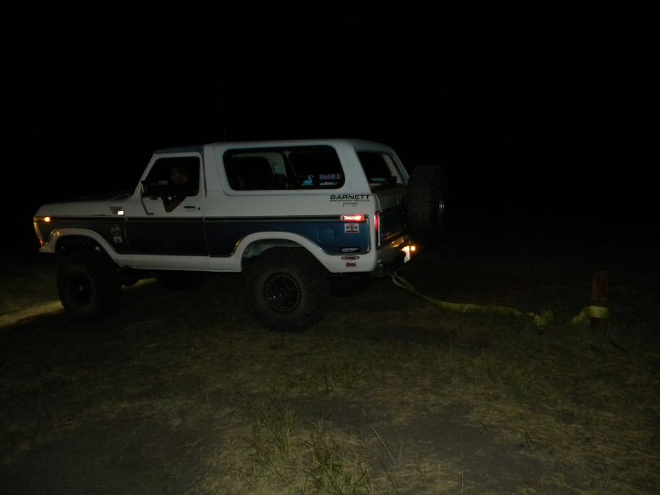 White and blue Ford Bronco with spare tire on back, lifted suspension
