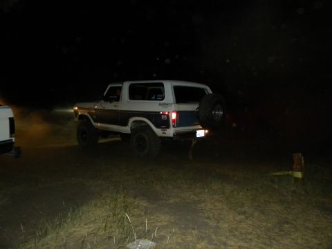 1992 Ford Bronco - A two-tone Ford Bronco is seen at night, with a spare tire mounted on the rear tailgate.