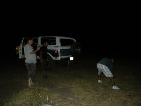 1992 Ford Bronco - A 1992 Ford Bronco is seen from the rear at night, with a spare tire mounted on the tailgate and three individuals nearby.