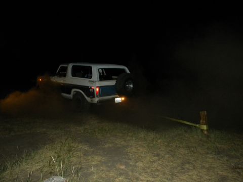 1992 Ford Bronco - Ford Bronco driving in dirt at night with a spare tire on the back.