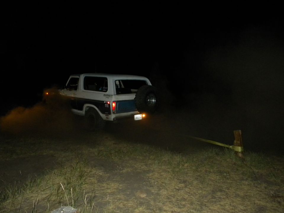 1978 Ford Bronco kicking up dirt at night, spare tire mounted on rear door