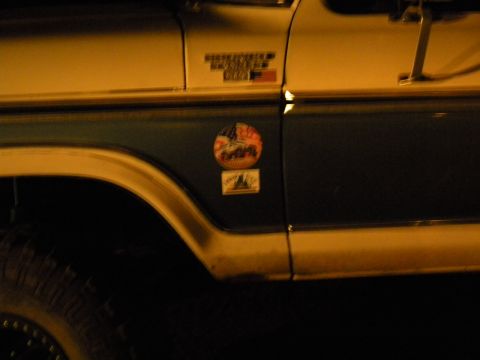 1992 Ford Bronco - A two-tone Ford Bronco is shown from the side, several decals on its rear door.