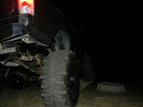 1992 Ford Bronco - Rear view of an off-road vehicle's axle and tire, taken in the dark.