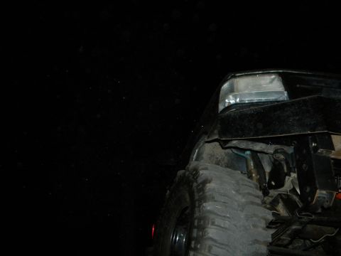 1992 Ford Bronco - A black 1992 Ford Bronco is seen from a low angle, focusing on the front tire and fender.