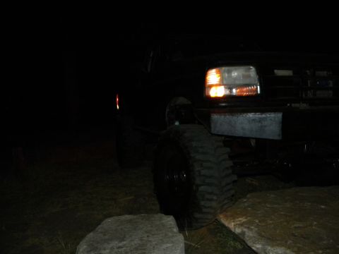 1992 Ford Bronco - 1992 Ford Bronco front corner visible at night, with large off-road tires.