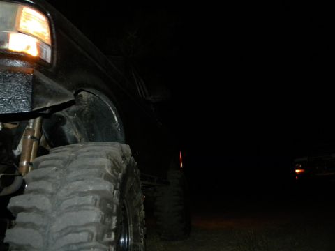1992 Ford Bronco - A black 1992 Ford Bronco is seen at night from a low angle, highlighting its large tires and modified front end.