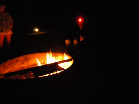 1992 Ford Bronco - A campfire burns brightly at night, with figures visible in the darkness around it.