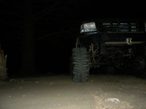 1992 Ford Bronco - A modified Ford truck is parked outdoors at night, showing its large tires and front-end modifications.