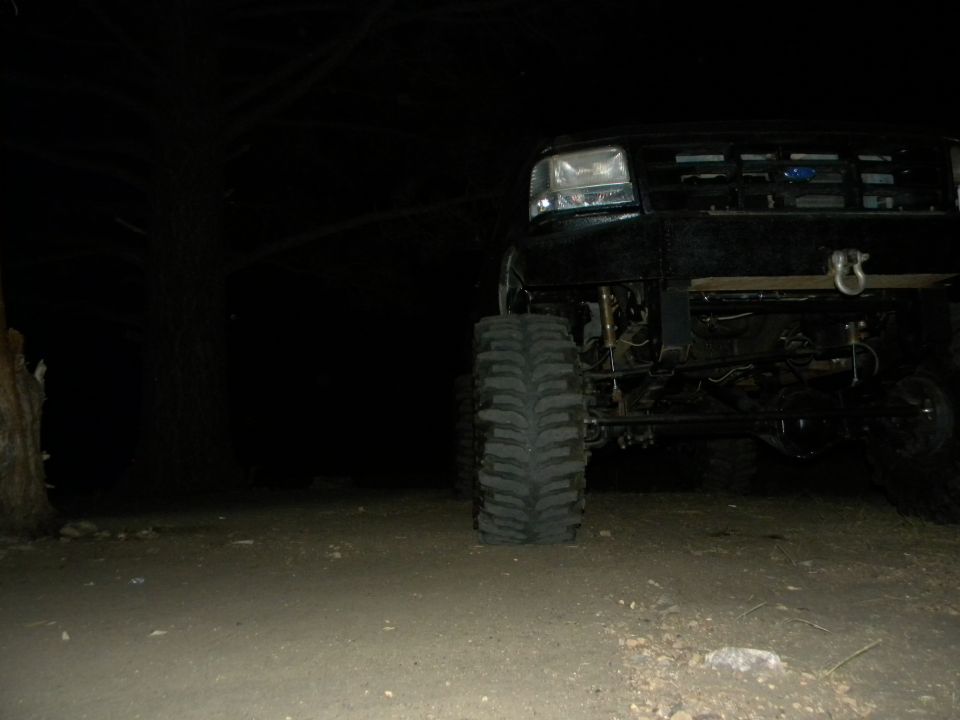 Front view of a black lifted Ford truck at night. It has large tires and a winch hook on the front bumper