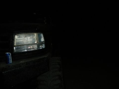 1992 Ford Bronco - Close-up of a 1992 Ford Bronco's headlight and tire, with a Bud Light can for scale.