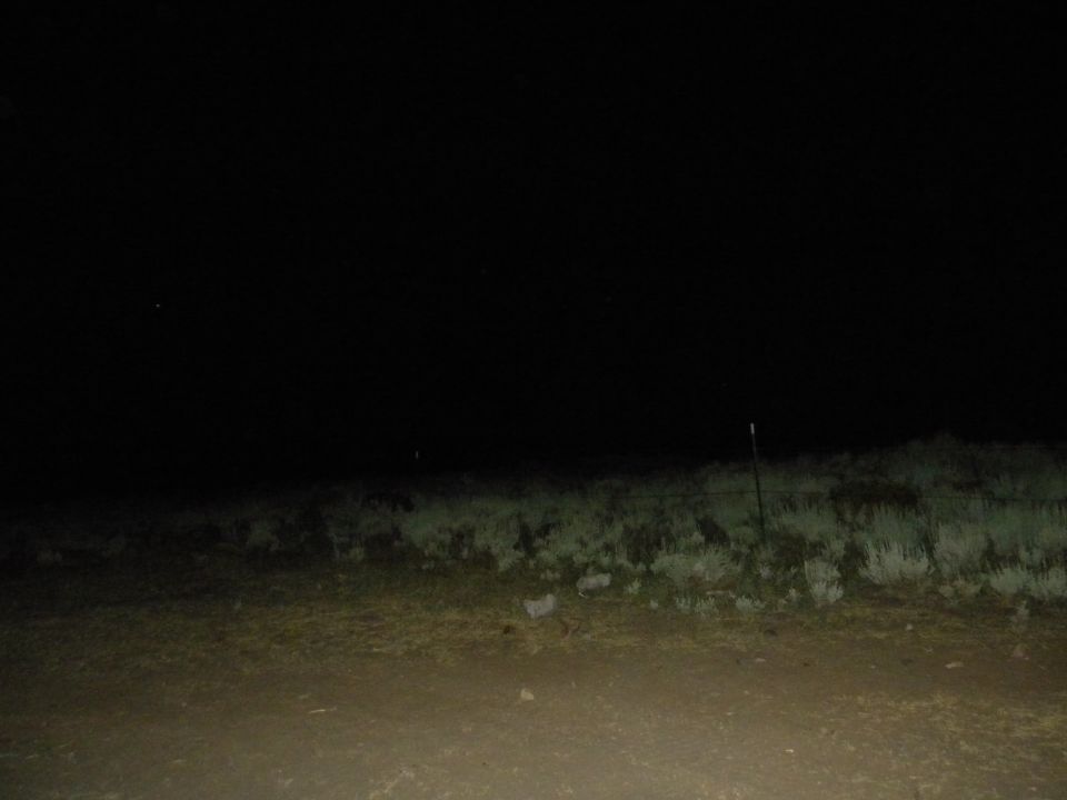 dark landscape with grass and fence posts at night, SUPERMOTORS.NET logo in corner