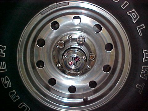 1996 Ford Bronco - Detail of a vehicle's wheel hub and tire, visible text on the tire sidewall and a central emblem.