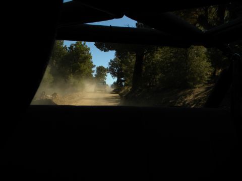 1992 Ford Bronco - A vehicle kicks up dust on a dirt road in a wooded area, with another vehicle ahead.