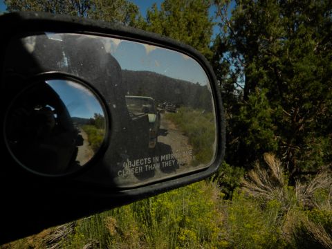 1992 Ford Bronco - Objects in mirror are closer than they appear, showing a line of trucks on a dusty trail.