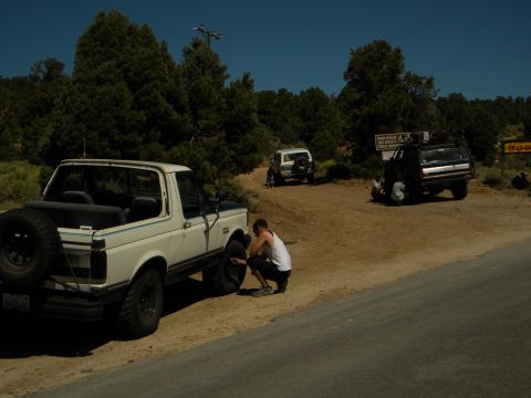 1992 Ford Bronco - A man works on a white Ford Bronco while two other vehicles are parked nearby.