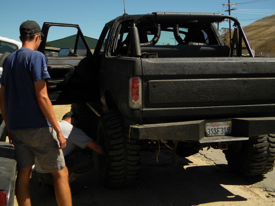 Black SUV rear view with people working on tire. California license plate 3SSF319