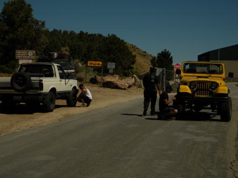 1992 Ford Bronco - Two off-road vehicles are stopped on the side of a road, with people attending to their tires.