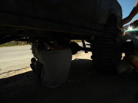1992 Ford Bronco - Mechanics work on the undercarriage of a heavily modified off-road vehicle.