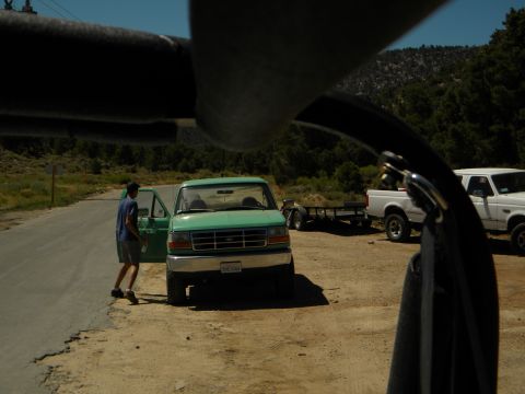 1992 Ford Bronco - A green Ford F-150 pickup truck is parked on a dirt lot with its driver's door open, while a white Ford pickup is parked nearby.