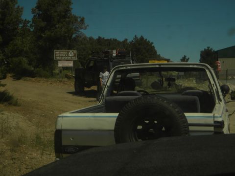 1992 Ford Bronco - A white SUV with a spare tire on the back is parked near a sign in a wooded area.