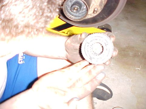 1996 Ford Bronco - A person holds a white hub assembly, with a yellow tool and part of a brake rotor visible in the background.