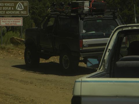 1992 Ford Bronco - 1992 Ford Bronco on a dirt road with a sign indicating a forest adventure pass is required.