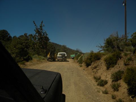 1992 Ford Bronco - A convoy of SUVs and a Jeep travel down a dusty mountain road under a clear blue sky.