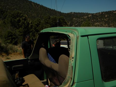 1992 Ford Bronco - View from the back seat of a green truck, looking towards the front with two people inside and one standing outside.