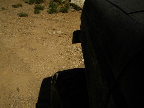 1992 Ford Bronco - A close-up view of a vehicle's interior seat and tire, set against a backdrop of a dry, dusty landscape.