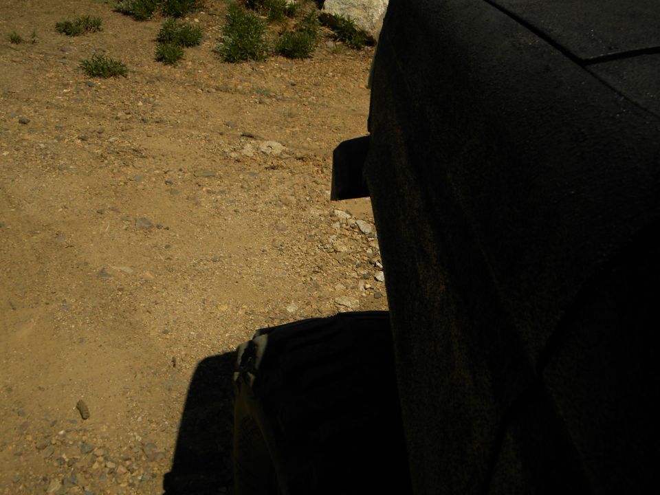 Black textured seat and tire in a dirt lot