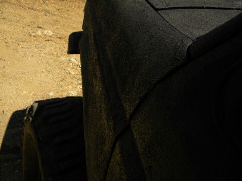1992 Ford Bronco - Close-up view of the textured rear quarter panel and tire of a black SUV.