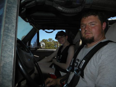 1992 Ford Bronco - Two individuals are inside a vehicle, one driving and the other in the passenger seat, with racing harnesses visible.