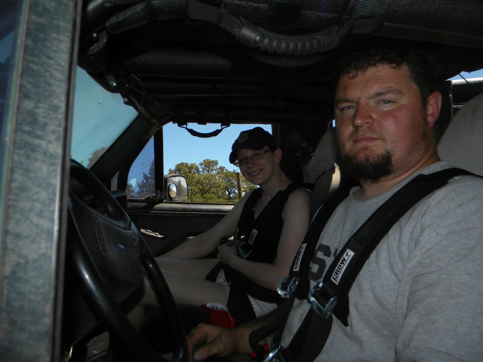 Interior of a modified SUV with two people wearing racing harnesses