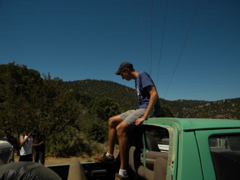 1992 Ford Bronco - A group of people are gathered around a green truck in a rural, hilly area under a clear blue sky.