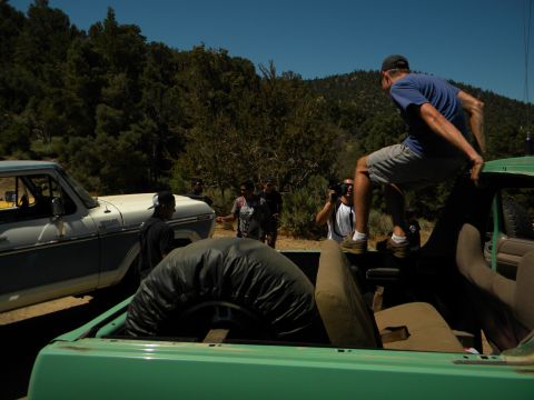 1992 Ford Bronco - Two trucks are parked in a wooded area with several people gathered around.