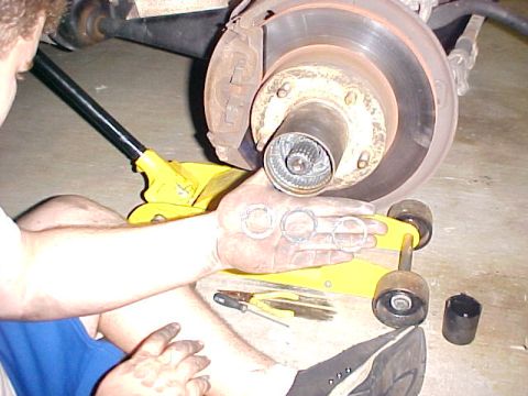 1996 Ford Bronco - Close-up of a vehicle's wheel hub assembly being serviced, with a person holding bearing races.