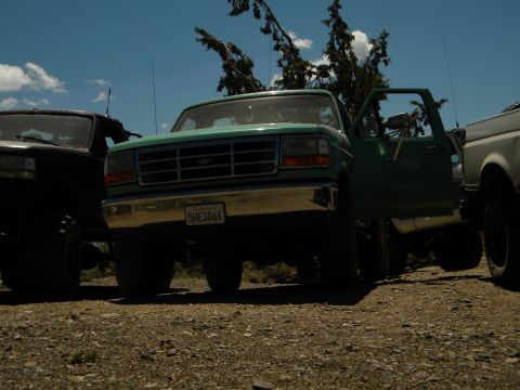 1992 Ford Bronco - Front view of a green 1992 Ford Bronco, parked outdoors with other vehicles.