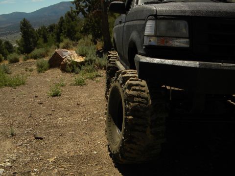 1992 Ford Bronco - Modified 1992 Ford Bronco with aggressive off-road tires parked on a dusty trail.